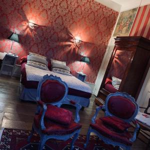 a bedroom with a bed with red walls and two chairs at Chambres d'Hôtes Les Foulons in Douai