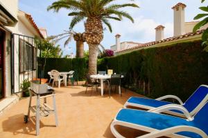 eine Terrasse mit Stühlen, Tischen und Palmen in der Unterkunft El Retiro 29 in Denia