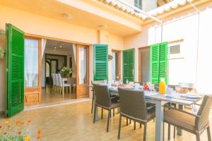 - une salle à manger avec volets verts, table et chaises dans l'établissement Ca Sa Tia Vicari, à Selva