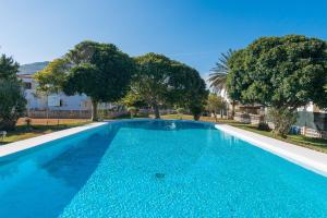 a blue swimming pool with trees in the background at Ropit in Port d'Alcudia