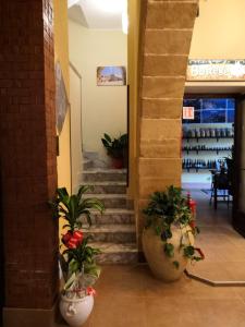 un pasillo con escaleras y macetas en una tienda en Fratelli Clemente Spa and Hotel, en Castelvetrano Selinunte