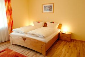 Un dormitorio con una cama con sábanas blancas y rosas rojas. en Pension Bergterrasse, en Annweiler am Trifels