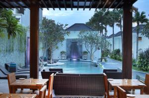 a resort with a swimming pool and tables and chairs at Daluman Villas in Seminyak