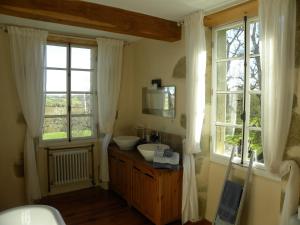 a bathroom with a sink and two windows at Maison Olleris in Couloumé-Mondébat