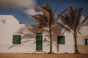 un edificio bianco con due palme di fronte di La Pardela Excellence Apartamentos a Caleta de Sebo