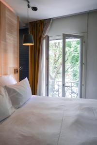 a bedroom with a large white bed with a window at Le Citizen Hotel in Paris