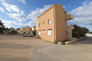a building with a car parked in a parking lot at Apartments Karolina in Novalja