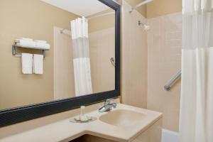 Super 8 by Wyndham Belleville St. Louis Area في بيلفيل: حمام مع حوض ومرآة