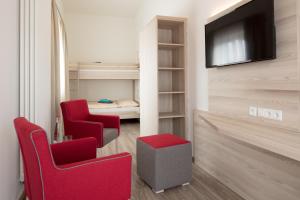 a living room with two red chairs and a television at Hotel Gudrun in Riedlingen