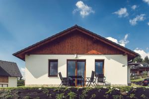 ein weißes Haus mit Stühlen davor in der Unterkunft Residence Lipno in Lipno nad Vltavou