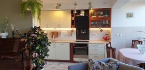 a kitchen with white cabinets and a table with a chair at Family Apartment Nida in Nida