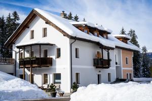 a white house with snow on the roof at Apartments & Relax Greta in Dobbiaco