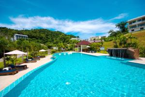 a pool at a resort with chairs and a waterfall at PS Hill Resort Phuket Patong - SHA Plus in Patong Beach