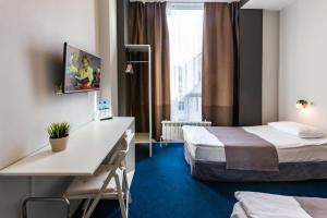 a hotel room with two beds and a desk at Hotel England Tyumen Center in Tyumen