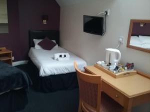 um quarto de hotel com uma cama e uma secretária com um computador em The Prince Consort em Southampton
