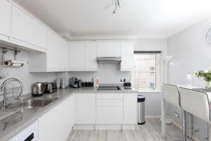 a white kitchen with white cabinets and a sink at amazing apartments - Annandale St near The Playhouse - Free Parking in Edinburgh