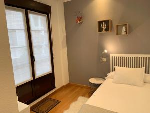 a small bedroom with a bed and a window at MenVal16 in Gijón
