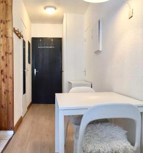 einen weißen Tisch und Stühle in einem Zimmer mit Tür in der Unterkunft Le Balme Studio WiFi/Parking/Balcony in Chamonix-Mont-Blanc