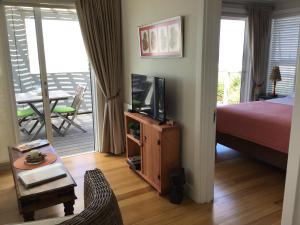a bedroom with a bed and a television and a balcony at Chez James in Yzerfontein