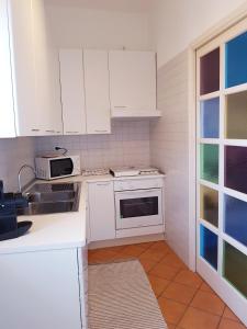 a kitchen with white cabinets and a sink at Alloggio Primosole in Fossano