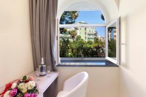 Habitación con ventana y mesa con un jarrón de flores en Palazzo Tritone & Abagnale en Sorrento