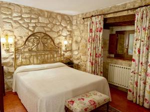 a bedroom with a bed and a stone wall at Hotel Tres Coronas de Silos in Santo Domingo de Silos