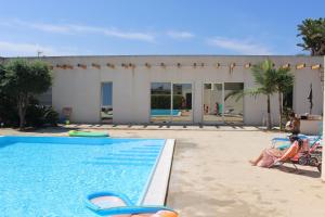 a pool with two people sitting in chairs next to a house at Villetta di Nonna Giovanna in Marsala