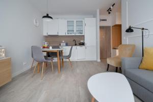 kuchnia i salon ze stołem i krzesłami w obiekcie Apartament Tuwima Park w Olsztynie