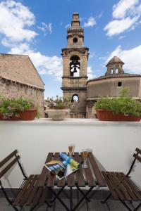 einen Tisch und Stühle auf einem Balkon mit einem Uhrturm in der Unterkunft Overseas - Appartamento Attico - Palazzo San Matteo in Palermo