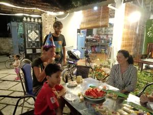 grupa ludzi siedząca przy stole i jedząca jedzenie w obiekcie Khai Yen Tam Coc Hostel w mieście Ninh Binh
