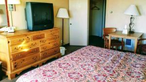 Habitación de hotel con cama y tocador con TV en Western Ridge Motel en Wendover