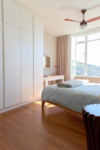 a white bedroom with a bed and a window at Breathtaking views, brand new renovated apartment in Cape Town