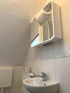 a bathroom with a sink and a mirror at Apartmenthaus Seestern in Neßmersiel +36 photos