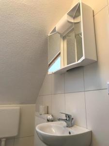 a bathroom with a sink and a mirror at Apartmenthaus Seestern in Neßmersiel