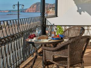 una mesa y sillas en un balcón con vistas al océano en Royal York & Faulkner Hotel, en Sidmouth