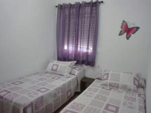 2 camas en una habitación con una mariposa en la pared en Casa 100m2, en Chiclana de la Frontera