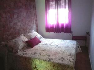 1 dormitorio con cama con almohada y ventana en Casa 100m2, en Chiclana de la Frontera