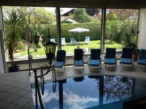 ein Pool mit Stühlen, einem Tisch und einem Sonnenschirm in der Unterkunft Hotel Roter Hahn - Bed & Breakfast in Garmisch-Partenkirchen