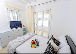 a white bedroom with a couch and a television at Happy Villas Mykonos in Kalafatis