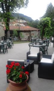 um pátio com mesas e cadeiras e um vaso de flores vermelhas em La Foresta Albergo Ristorante Pizzeria em Badia Prataglia