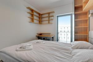 Un dormitorio con una cama blanca y una ventana. en Wave Apartments - Cztery Oceany, en Gdansk