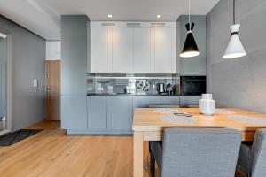 Una cocina con una mesa de madera y gabinetes blancos. en Wave Apartments - Cztery Oceany, en Gdansk
