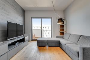 Una sala de estar con un sofá y un televisor de pantalla plana. en Wave Apartments - Cztery Oceany, en Gdansk