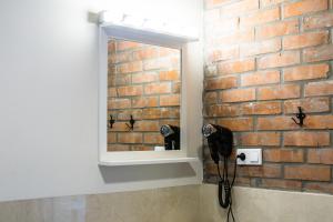 a bathroom with a mirror and a brick wall at Apartamenty Madera in Katowice