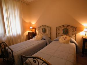 sypialnia z 2 łóżkami z białą pościelą i oknem w obiekcie Villa Teresa w mieście Massa Marittima