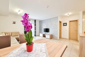 uma sala de estar com uma mesa e um vaso com flores roxas em Apartman Leon em Umag