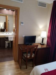 Hotel Arcco Ubeda في أوبيذا: غرفة في الفندق مع مكتب عليه جهاز كمبيوتر