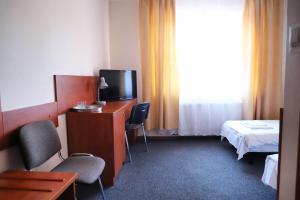 a hotel room with a tv and a bed and a desk at Hotel Julian&oacute;w in Warsaw