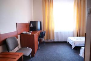 ein Hotelzimmer mit einem TV, einem Bett und einem Schreibtisch in der Unterkunft Hotel Julianów in Warschau