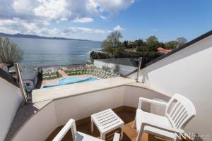 balcón con sillas y vistas al agua en Hotel Spa Nanin Playa, en Sanxenxo